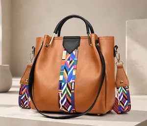 Detail of tan faux leather handbag featuring a colorful geometric ethnic style strap