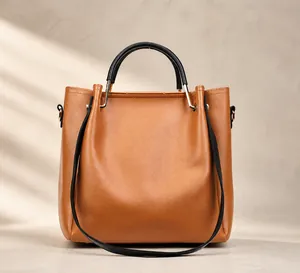 Rear view of brown leather handbag featuring black round handles and gold hardware details