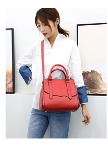 Close-up of red lychee textured handbag with gold zipper details and adjustable shoulder strap