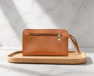 Close-up of a brown synthetic leather clutch bag with metal zipper and wristlet strap