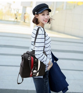 Close-up of stylish brown leather backpack with contrast stripes and panda charm