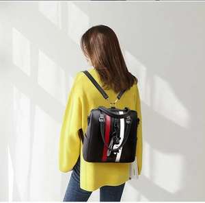Detail of black leather backpack with red white stripes and cute bear pendant charm