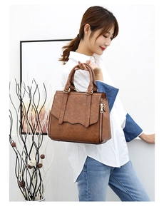 Detail view of brown vintage tote bag with wavy flap design and metal zipper accents