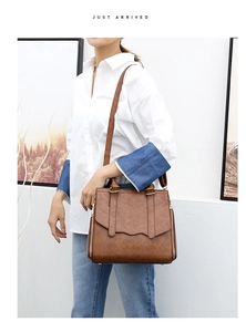 Detail of a large brown vintage tote bag featuring dual handles and a long shoulder strap