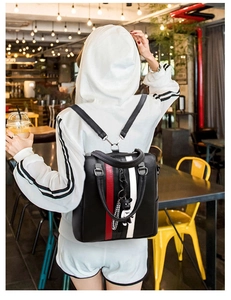 Detail showing back view of black backpack with red and white stripes and bear pendant