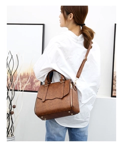 Detail of dark brown leather tote bag with gold hardware and adjustable shoulder strap
