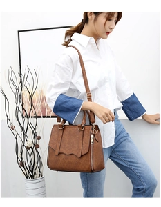 Detail of a brown vintage leather handbag with decorative side zippers and gold hardware