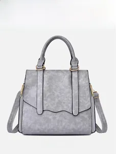 Front view of grey faux leather tote bag with gold hardware and decorative side zippers