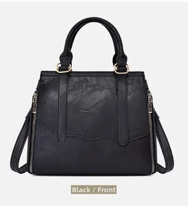 Front view of black pebbled leather tote bag with gold ring hardware and side zippers