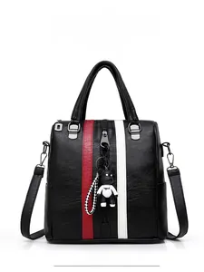 Detail of black faux leather bag with red and white stripes and cartoon bear charm