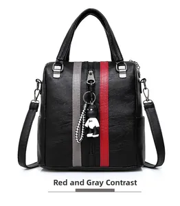 Detail of black lychee grain leather backpack with red and grey stripes and bear charm