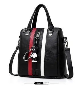 Side view of a black pebbled PU leather backpack with red white stripes and a bear charm