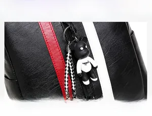 Close-up of black pebble leather handbag featuring striped tape and a bear charm