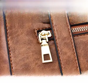 Detailed close-up of golden metal zipper and vintage brown textured faux leather on handbag