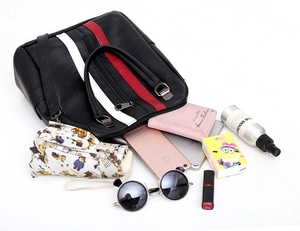Detail showing high-capacity black handbag interior holding phone, wallet and umbrella