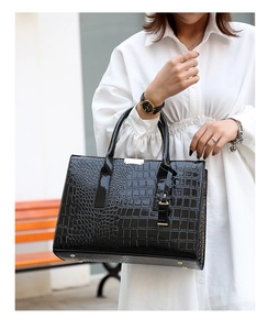 Gros plan d'un sac cabas noir à motif crocodile brillant avec détails métalliques dorés
