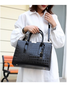 Détail d'un sac à main brillant à motif crocodile avec des finitions dorées élégantes