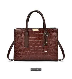 Détail du sac à main marron foncé à texture crocodile avec fermoir et breloque en métal doré