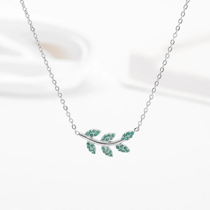 Détail du pendentif feuille avec cristaux verts sur une fine chaîne en argent
