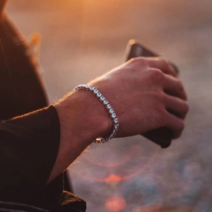 Gros plan d'un bracelet tennis en argent avec zircons sur un poignet au coucher du soleil