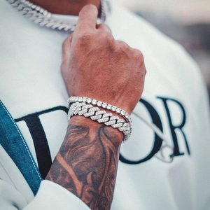 Détail de la chaîne tennis argentée et du bracelet cubain sur poignet tatoué
