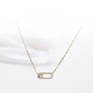 Détail du pendentif trombone doré serti de zircons avec un grand cristal au centre