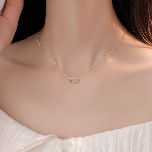 Collier trombone doré avec cadre en diamants et pendentif émeraude sur femme