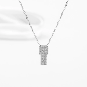 Gros plan d'un pendentif croix géométrique en argent orné de pierres de zircone cubique