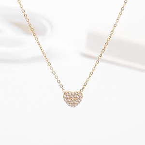Macro di una collana con pendente a cuore dorato con zirconi brillanti incastonati