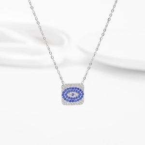 Detailed view of silver evil eye necklace with blue zircon pavé on white silk background