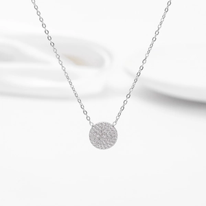 Detailed close-up of a silver pavé-set round pendant with micro-zirconia on a link chain