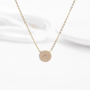 Macro detail of gold circular pendant with paved sparkling crystals and fine chain