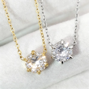 Gros plan de colliers plaqués or 18 carats et argent avec pendentifs zircon sur de la soie