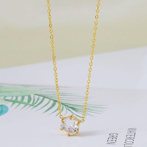 Macro détaillée du serti à six griffes et du zircon rond brillant sur le collier doré