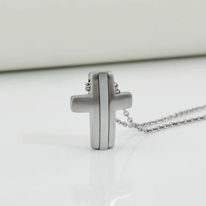 Macro shot of silver cross pendant with brushed texture and polished vertical lines