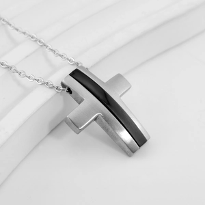 Macro detail of silver cross pendant with black inlay and brushed metal finish on O-chain