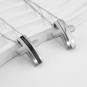 Close-up of minimalist stainless steel cross pendants with brushed metal finish