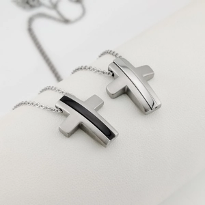 Macro shot of brushed and polished cross pendants on a white leather display stand