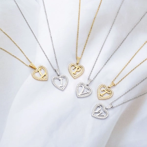 Détail de pendentifs cœur évidés avec zircone et alphabet gravé sur de la soie