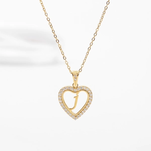 Macro d'un pendentif cœur doré avec pavé de cristaux et lettre J au centre
