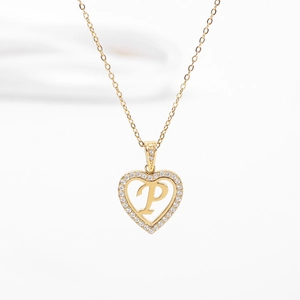Détail d'un collier cœur doré avec une lettre P sertie et une fine chaîne à maillons