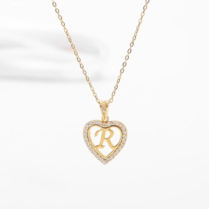 Détail du pendentif en cœur avec lettre R et cristaux pavés sur une chaîne dorée
