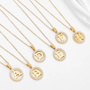 Detailed close-up of golden initial necklaces with sparkling pavé zircon round pendants