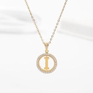 Macro detail of a gold stainless steel necklace with a zircon-encrusted letter I pendant