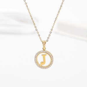 Detailed close-up of a gold-plated necklace with a zircon-encrusted round letter J pendant