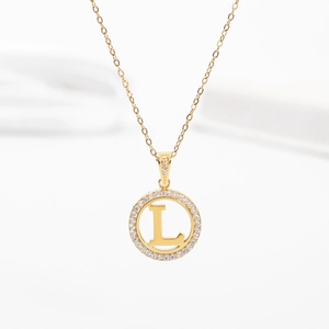 Detailed view of golden pendant necklace with letter L and sparkling crystal halo
