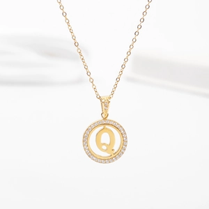 Detailed close-up of golden round hollow pendant with letter Q and sparkling crystals