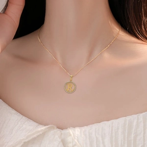 Minimalist gold stainless steel necklace with round cutout R pendant and crystal border