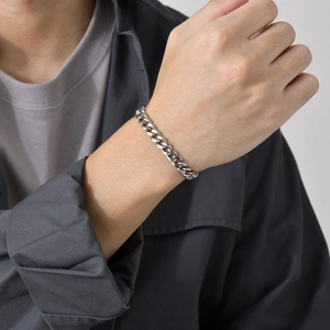 Macro view of polished silver steel Cuban link bracelet on male model's wrist