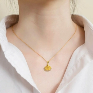 Close-up of golden shell pendant necklace with sparkling stones on a model